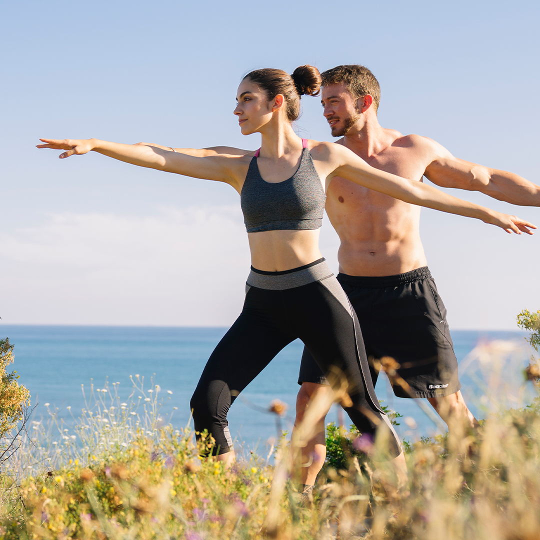 i couple doing balance exercise beach FreePik