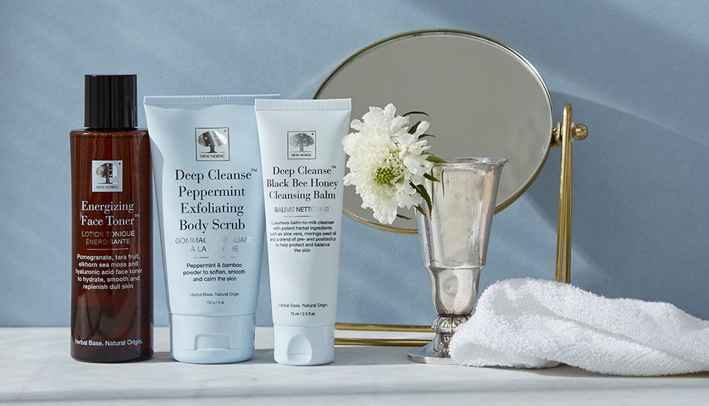 a group of Cleansing body care products next to a silver cup and a white flower