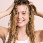 Vrouw met nat haar die glimlacht en een natuurlijke glans en gezonde uitstraling van het haar toont.