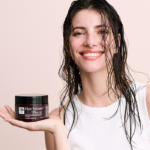 Beautiful woman with wet hair holding the Hair Volume™ Repair Mask, representing healthy shine and strength.