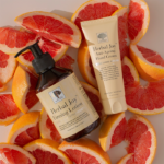 Herbal Joy™ Firming Lotion en Anti-Ageing Hand Cream op vers gesneden grapefruit.