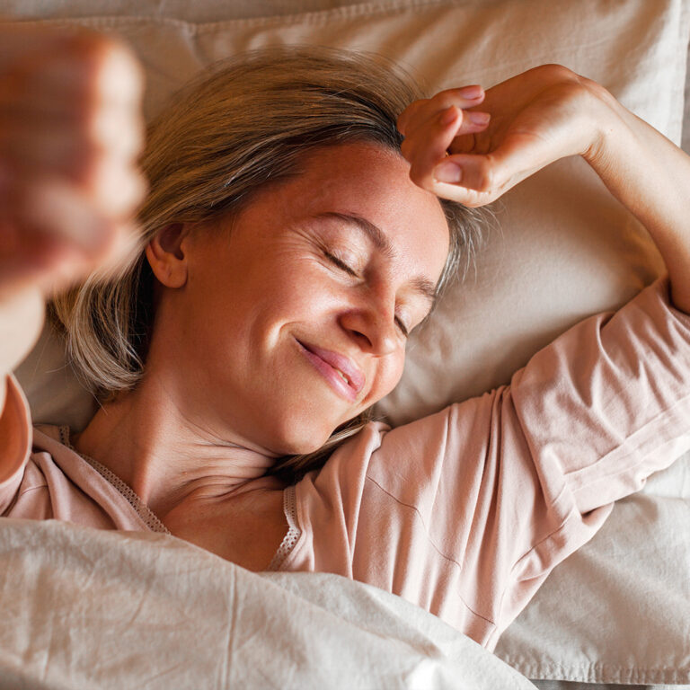Woman stretching in bed, morning wake-up routine and relaxation.
