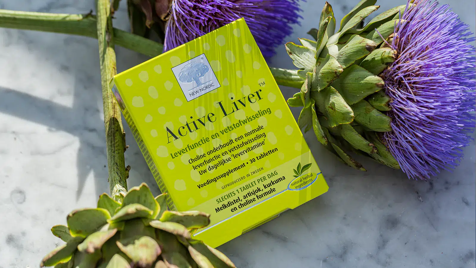 Active Liver™ verpakking tussen artisjokken en paarse distelbloemen op een marmeren oppervlak.